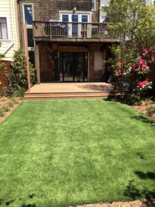 Well-maintained backyard with fresh green lawn and wooden deck.