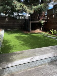 A small backyard with artificial grass and a built-in barbecue area.