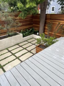 Modern backyard with stone pavers and wooden deck.