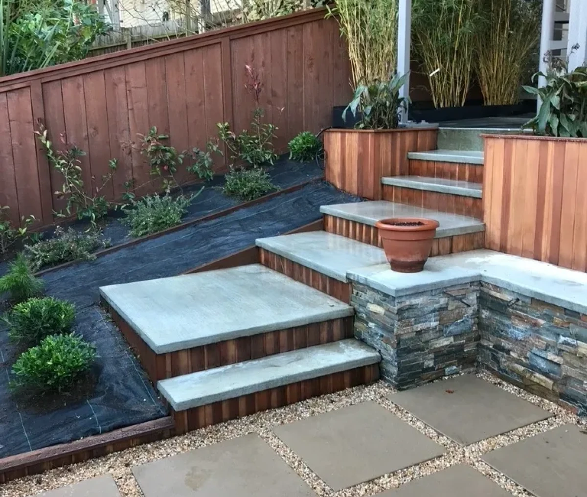 Modern backyard patio with stone steps and seating area.